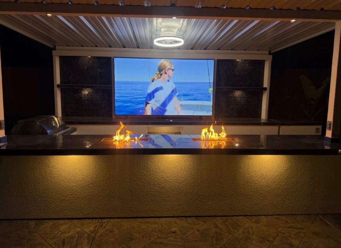 Outdoor cabana at night with illuminated shelves, under-counter lighting and a glowing fire feature