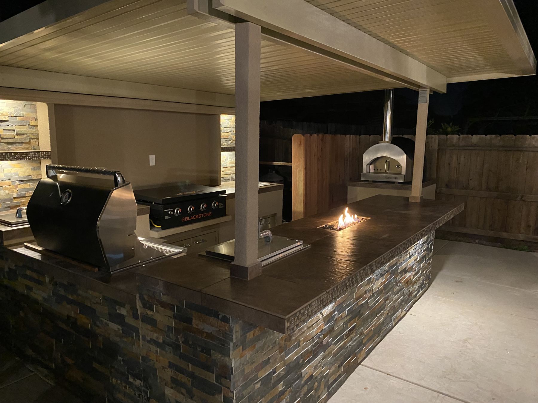 Custom covered outdoor kitchen at night built by Just BBQ Grills