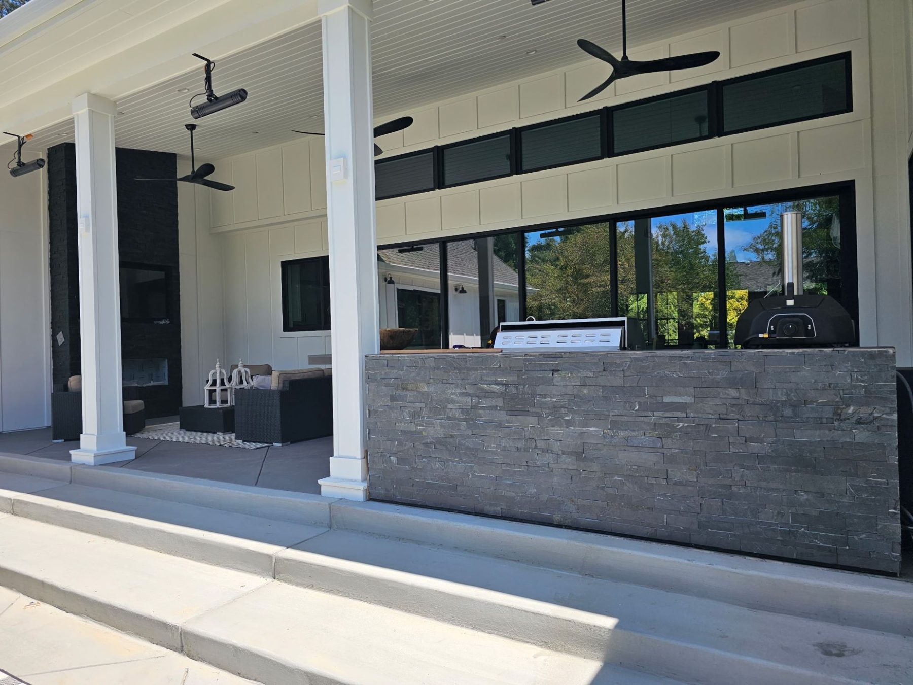 Front of a custom stacked-stone outdoor kitchen with stainless doors and drawers