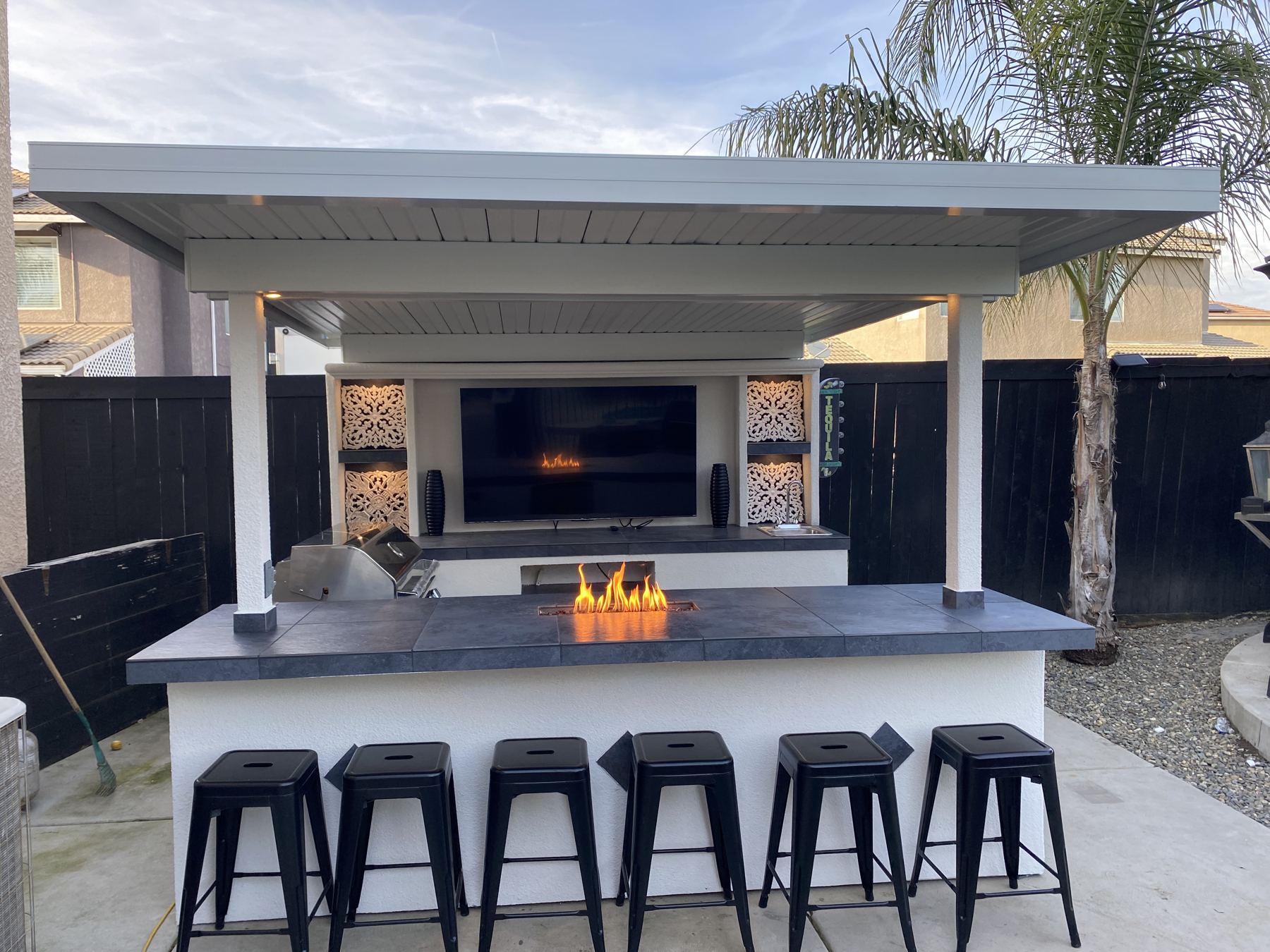 Covered entertainment cabana with TV wall, fire feature and six bar stools
